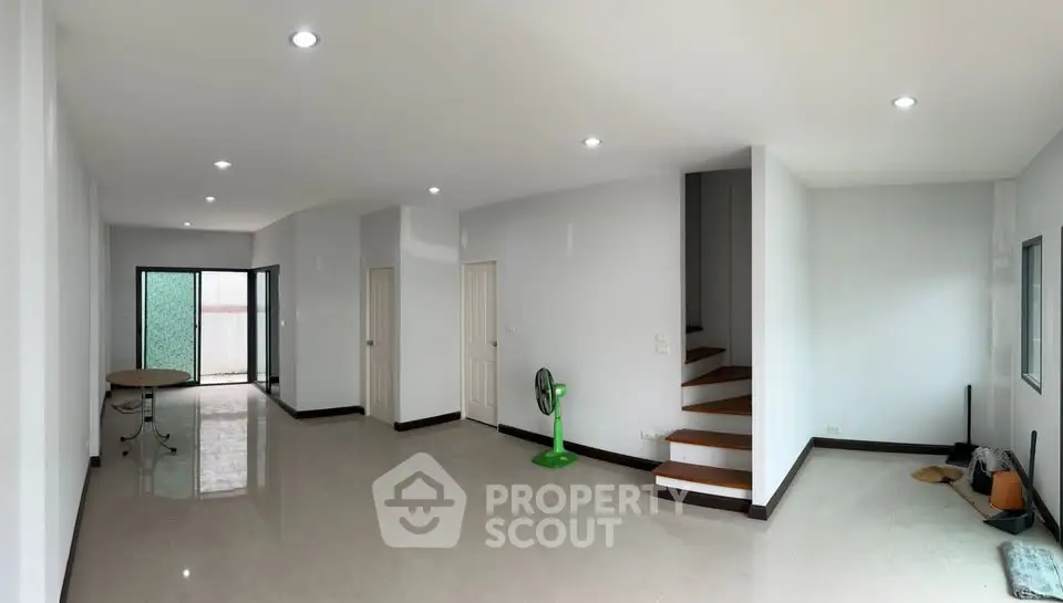Spacious open-plan living area with modern staircase and ample natural light.