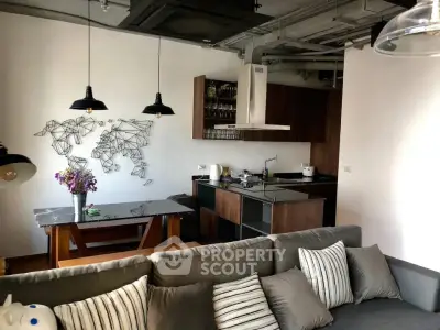 Modern living room with stylish kitchen, featuring industrial lighting and contemporary decor.