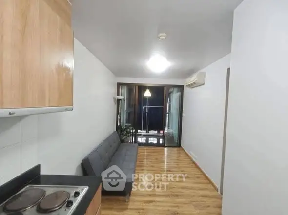 Modern apartment with sleek kitchen and cozy living area featuring wooden flooring and natural light.