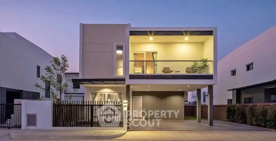 Modern two-story house with sleek design and illuminated balcony at dusk.