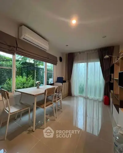 Bright dining area with large windows and garden view, featuring modern furniture and air conditioning.