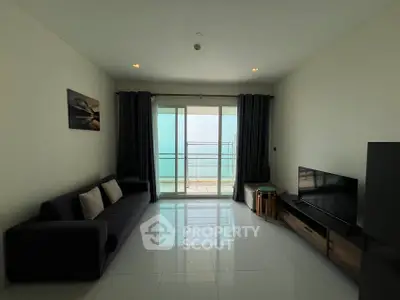 Modern living room with ocean view, sleek furniture, and large glass doors leading to a balcony.