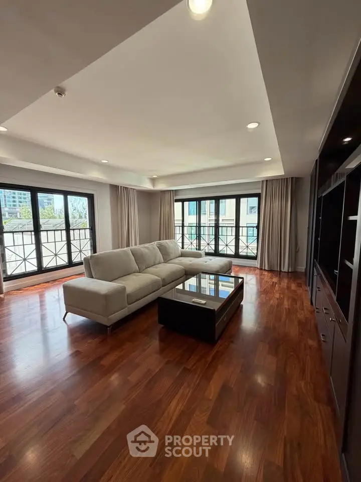 Spacious living room with elegant hardwood floors and large windows offering abundant natural light.