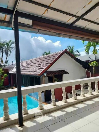 Charming poolside view from a spacious balcony with tropical surroundings.