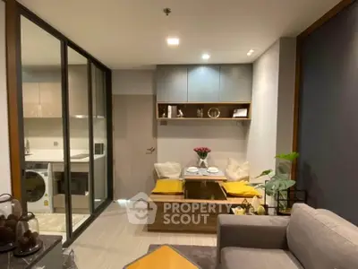 Modern living room with cozy dining nook and sleek kitchen in open layout apartment.