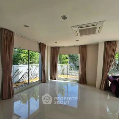 Spacious living room with large windows and garden view, perfect for natural light lovers.