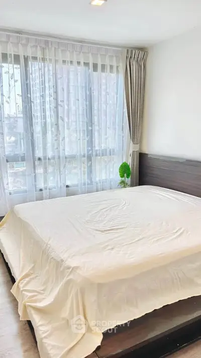 Spacious bedroom with large windows and modern decor in a high-rise apartment.