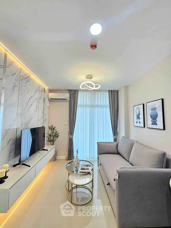 Modern living room with elegant decor, featuring a sleek sofa, stylish lighting, and a wall-mounted TV.