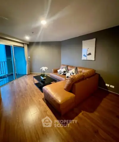 Spacious living room with modern decor and large leather sofa, featuring a cozy ambiance and wooden flooring.