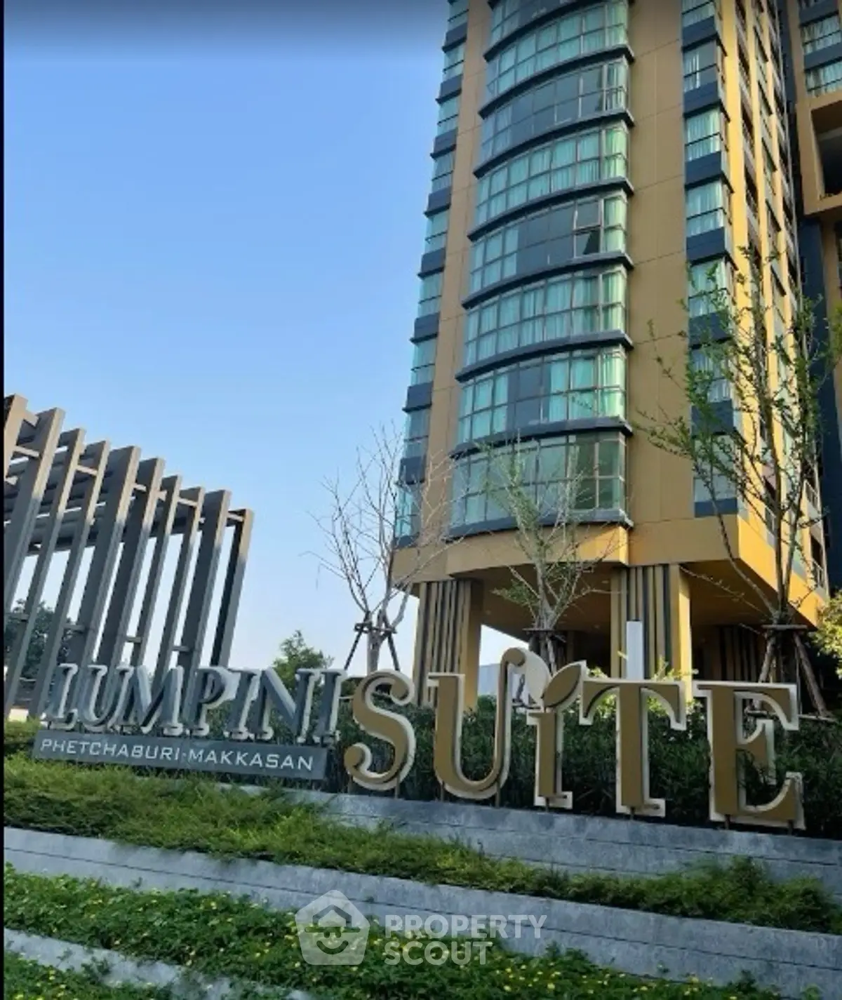 Modern high-rise building exterior with lush landscaping at Lumpini Suite Phetchaburi Makkasan.
