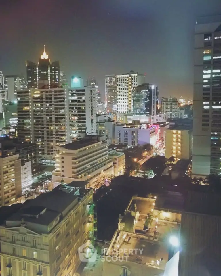 Stunning cityscape view of illuminated high-rise buildings at night, showcasing urban living and vibrant city life.