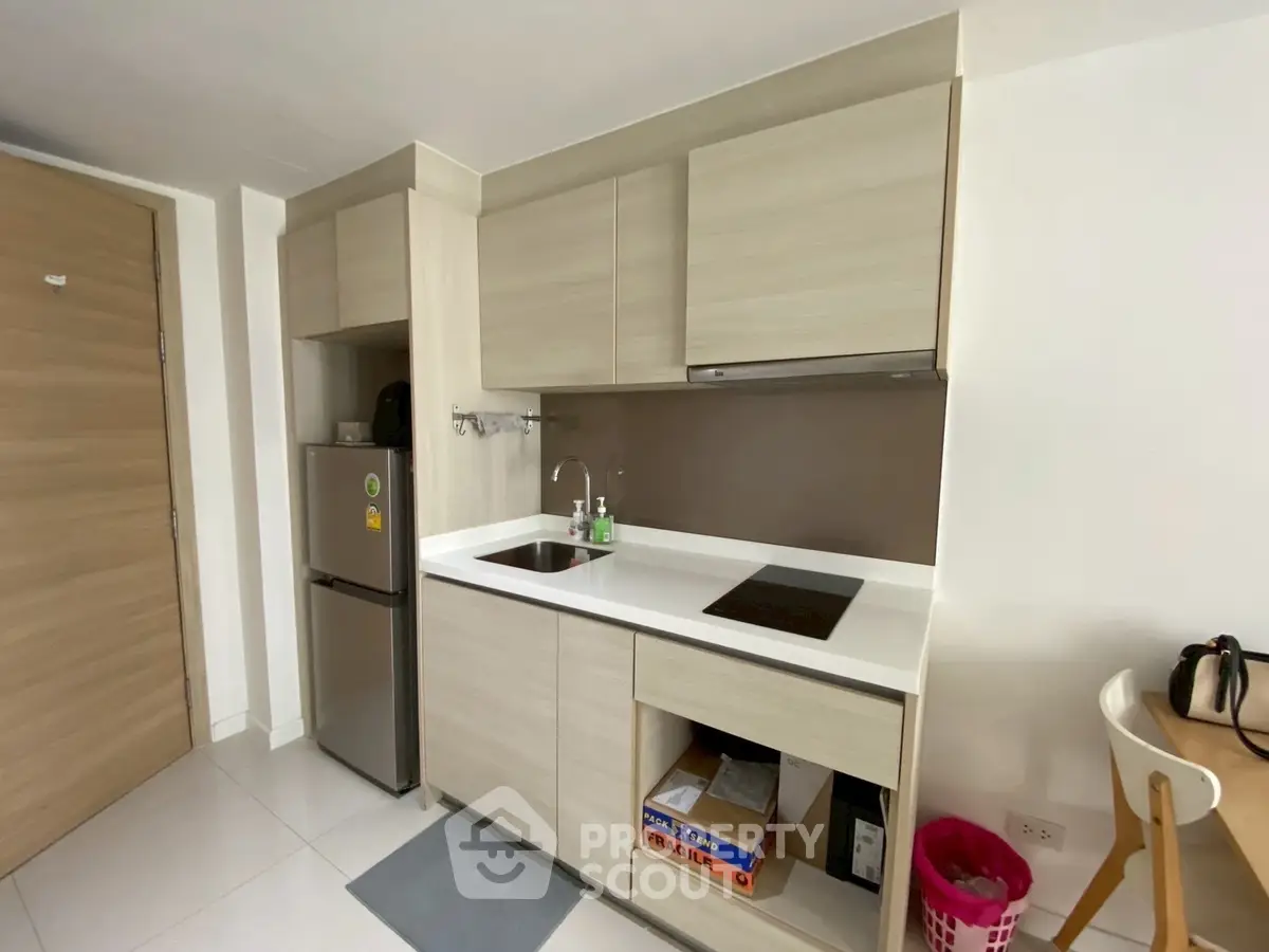 Modern compact kitchen with sleek cabinetry and built-in appliances in a cozy apartment.