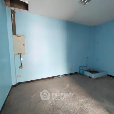Spacious empty room with blue walls and concrete floor, ideal for customization.
