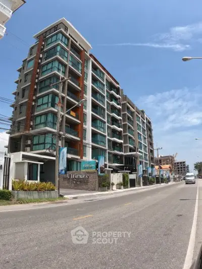 Modern multi-story residential building with glass balconies and street view.