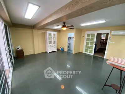 Spacious living room with modern ceiling fan and ample natural light, perfect for family gatherings.