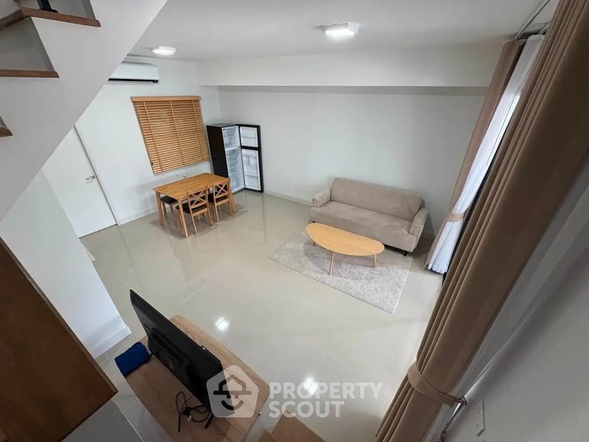 Modern living room with sleek furniture and open layout, featuring a cozy sofa and dining area.