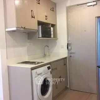 Compact kitchen with washing machine and microwave in modern apartment