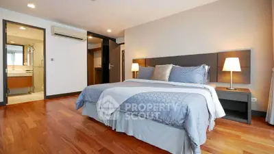 Spacious bedroom with modern decor and ensuite bathroom in a luxurious apartment.