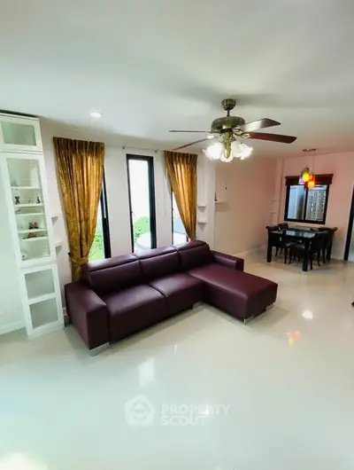 Spacious living room with modern sofa and dining area, ideal for family gatherings.