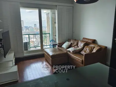 Cozy living room with leather sofa and city view balcony, perfect for relaxation.