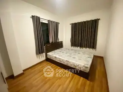 Cozy bedroom with wooden flooring and large windows for natural light.