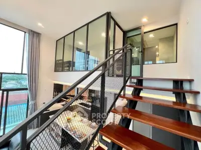 Modern loft apartment with stylish staircase and glass-walled mezzanine, offering a spacious and contemporary living area.