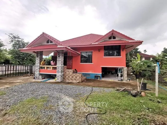 Charming red-roofed house with spacious front yard and lush greenery, perfect for serene living.