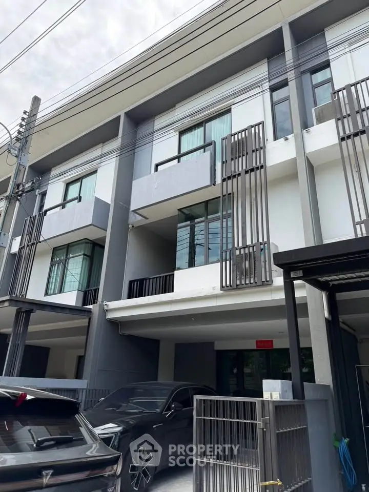 Modern townhouse exterior with sleek design and carport in urban setting.