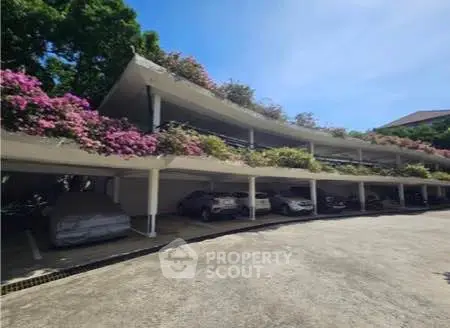 Charming covered parking area with lush greenery and vibrant flowers enhancing the aesthetic appeal.