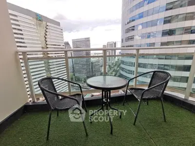 Stunning city view from a modern balcony with cozy seating area, perfect for relaxation.