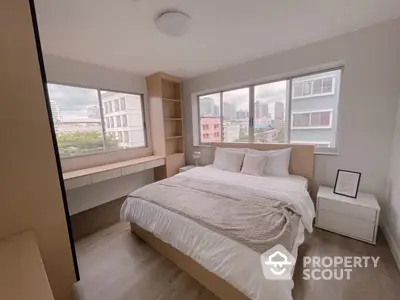 Spacious bedroom with large windows offering ample natural light and a serene city view, featuring a cozy bed and modern design.