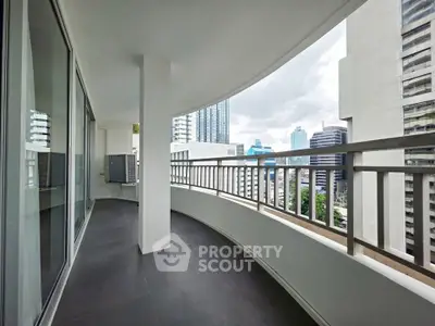 Spacious curved balcony with city skyline view in modern high-rise apartment.