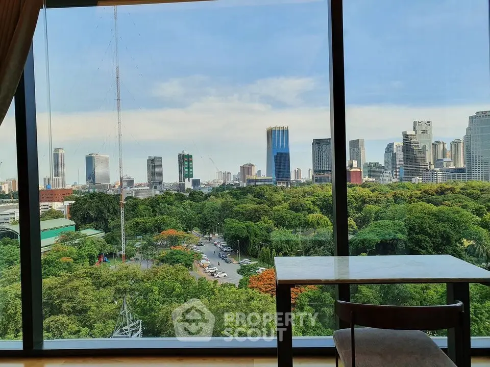 Stunning cityscape view from a high-rise window overlooking lush greenery and urban skyline.