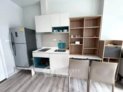 Modern kitchen with sleek cabinetry and stainless steel fridge in a compact apartment.