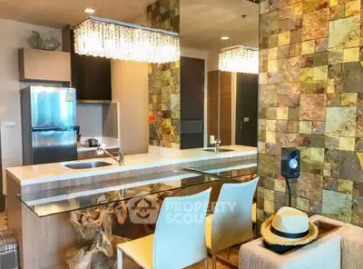Modern kitchen with stylish decor and unique wooden counter, featuring a sleek fridge and elegant lighting.