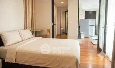Spacious bedroom with modern decor and wooden flooring in a stylish apartment.