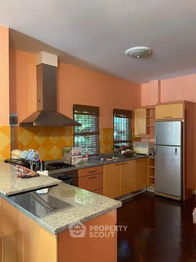 Spacious kitchen with modern appliances and vibrant orange decor.