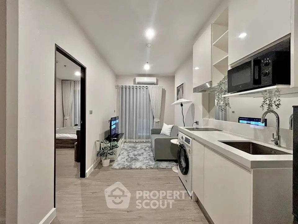 Modern open-plan living room and kitchen with washing machine and sleek decor