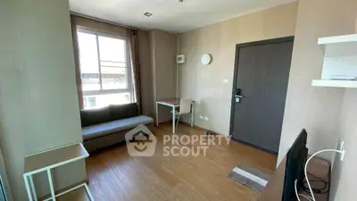 Modern living room with wooden flooring, sofa, and natural light from large window.