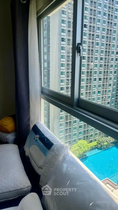 Modern high-rise apartment with pool view through large window, showcasing urban living at its finest.