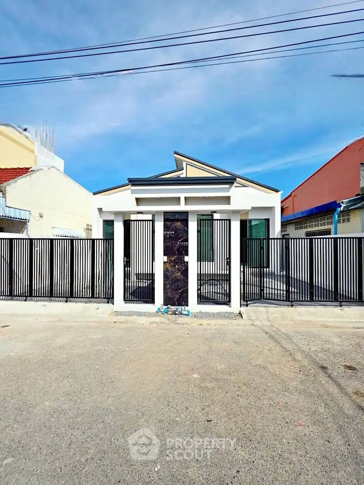 Modern single-story house with sleek black gate and minimalist design under clear blue sky.