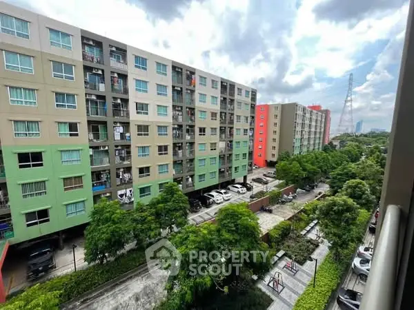 Spacious apartment complex with lush greenery and ample parking space.