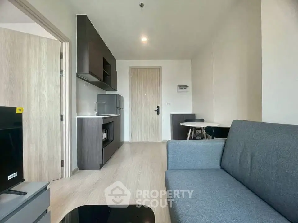 Modern living room with sleek furniture and open layout, featuring a cozy sofa and stylish kitchenette.