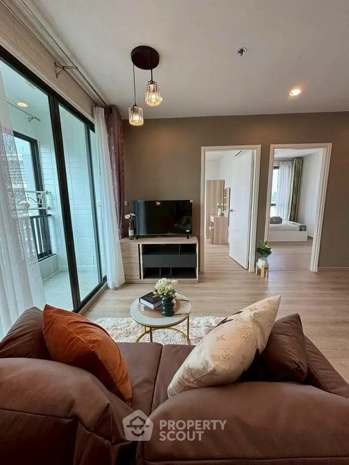 Modern living room with cozy sofa, TV, and balcony view in stylish apartment.