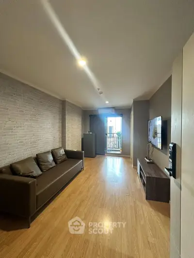 Spacious living room with modern decor and balcony access, featuring a sleek sofa and entertainment unit.