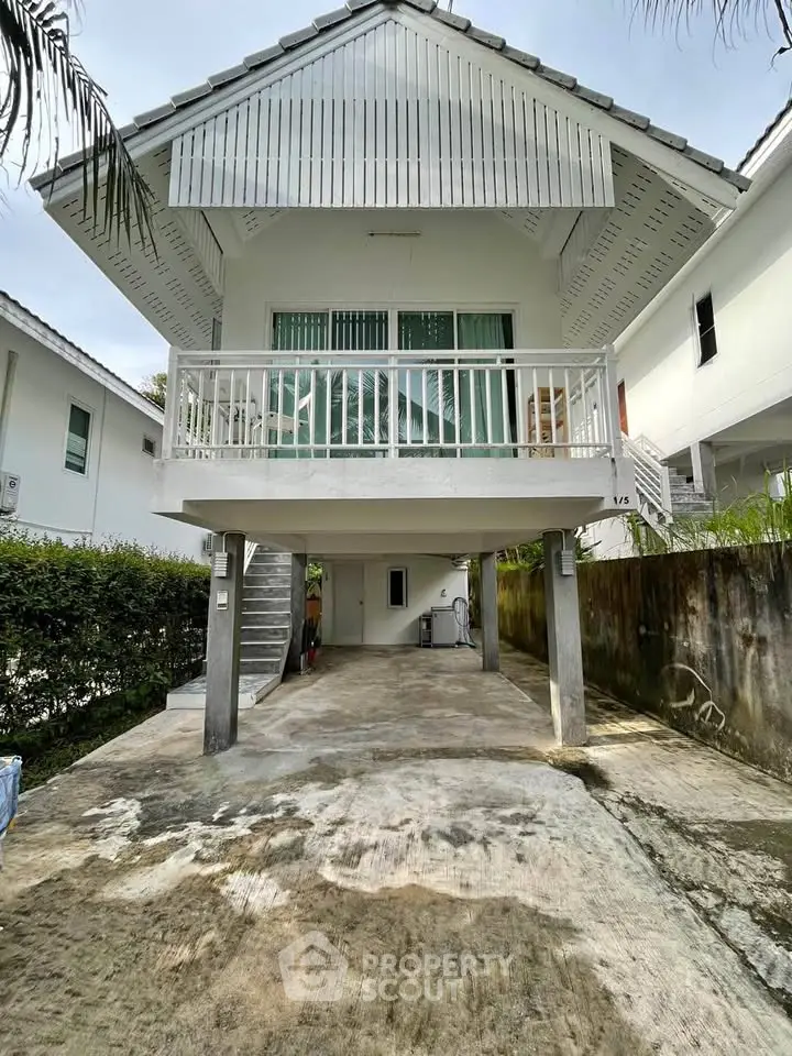 Charming elevated white house with spacious driveway and lush greenery, perfect for serene living.
