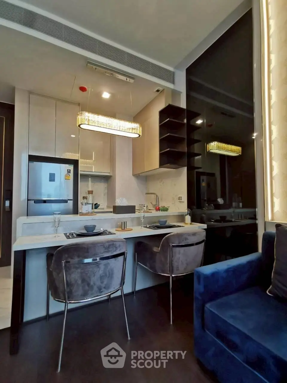 Modern kitchen with sleek design, featuring a dining area and stylish lighting in a contemporary apartment.