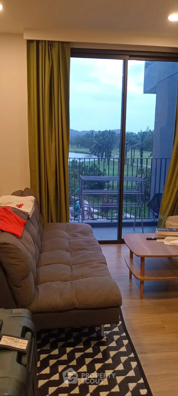 Modern living room with balcony view overlooking lush greenery and golf course.