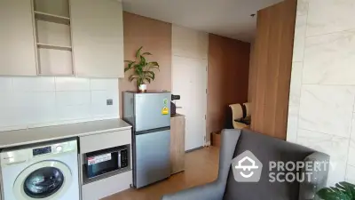 Modern apartment kitchen with washing machine, microwave, and fridge