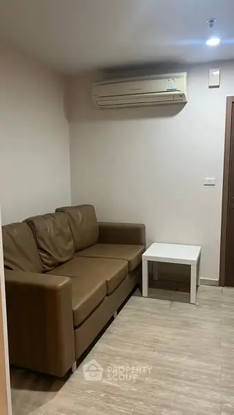 Cozy living room with brown leather sofa and air conditioning unit